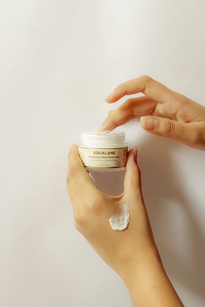 Close-up of hands applying squalane cream, highlighting skincare essentials.